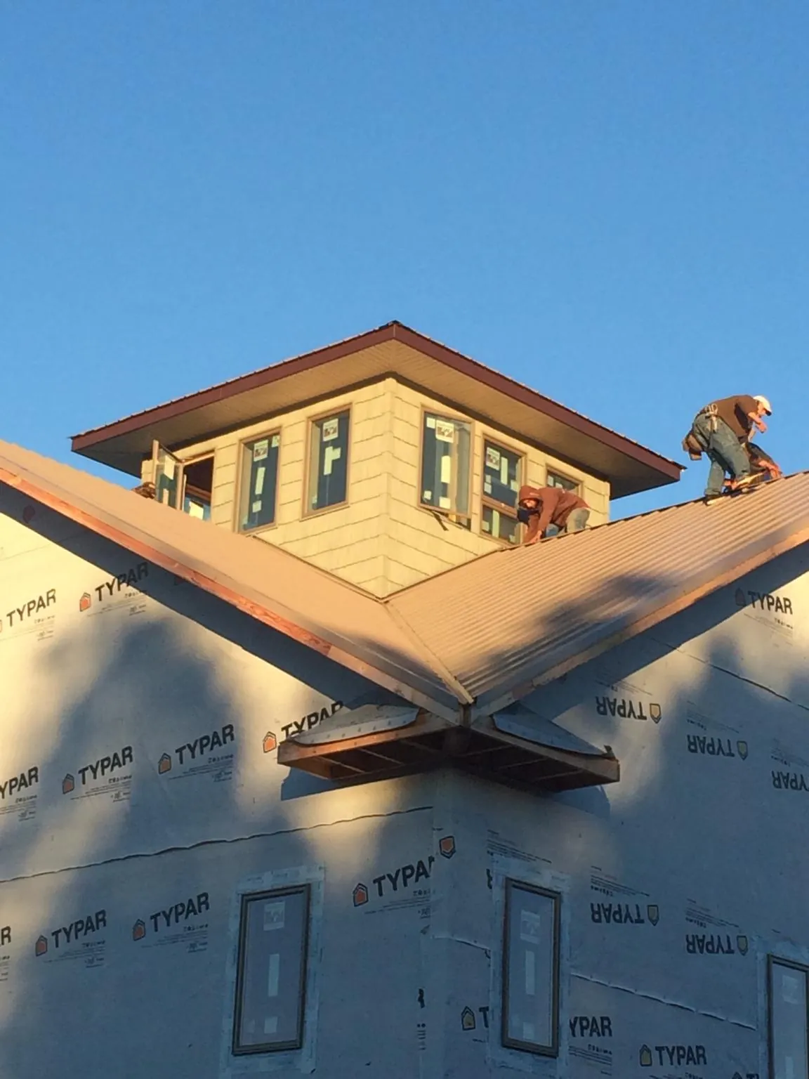 Roofers working around a rooftop cupola on a new metal roof at sunset — Roof Waterproofing in Annandale by Roofing Brothers